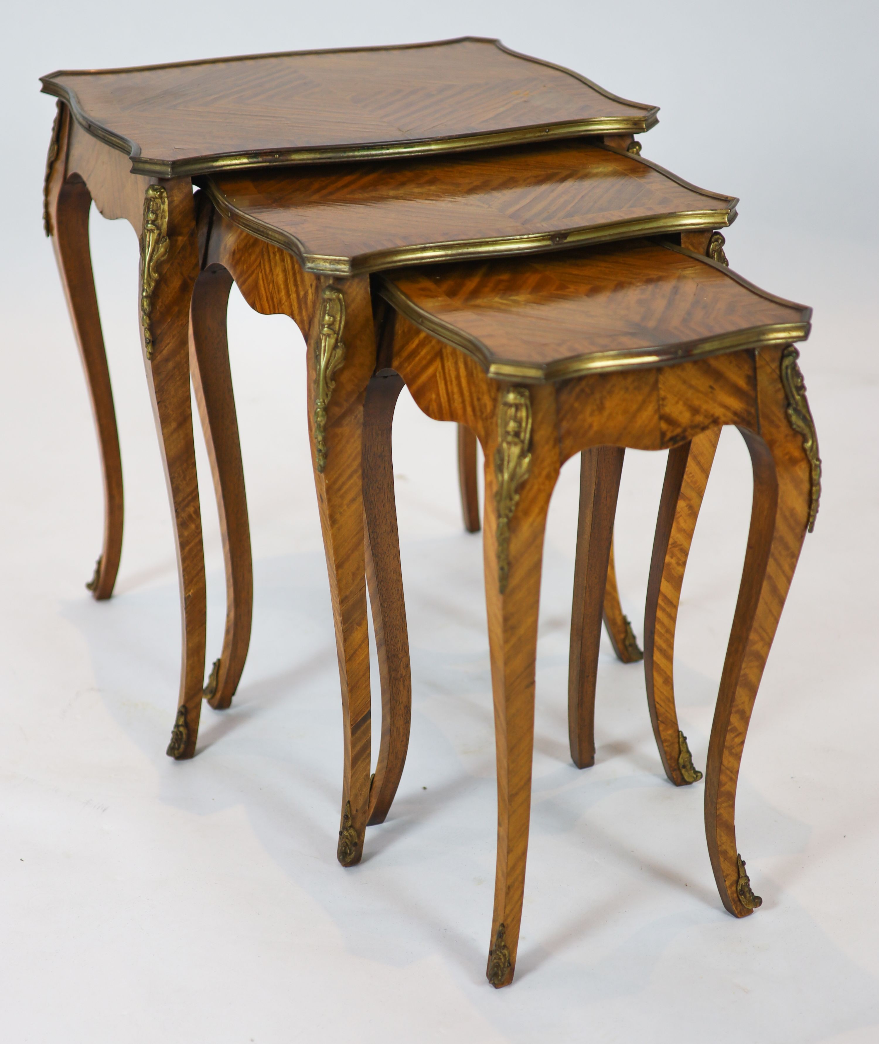 A nest of three Louis XV style ormolu mounted banded kingwood tables, with serpentine sides, on cabriole legs, width 51cm, depth 41cm, height 59cm